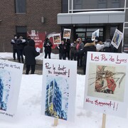 Des affiches de manifestants plantés dans la neige, devant un groupe de manifestants.