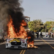 Plusieurs voitures brûlent dans une rue.