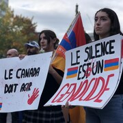 Des personnes tiennent des pancartes durant une manifestation.