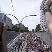 Vue de haut d'une foule de manifestants marchant dans une rue de Montréal, avec en premier plan, un bras levé vers le ciel.