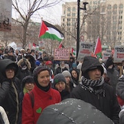 Une foule porte des pancartes pour dénoncer un génocide à Gaza.