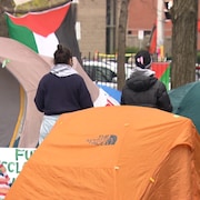Deux personnes qui marchent entre des tentes à l'Université d'Ottawa. 