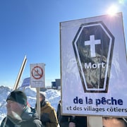 Une pancarte sur laquelle est écrit : mort de la pêche et des villages côtiers lors d'une manifestation de pêcheurs de crevette à l'hiver 2024.