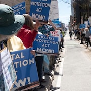 Des manifestants tiennent des pancartes. Ils réclament une loi sur la protection côtière au plus vite. 