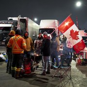 Des camionneurs réunis autour d'un barbecue à la tombée de la nuit.