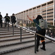 Une manifestante fait des doigts d'honneur à des policiers anti émeute qui se dirigent vers elle, dans les rues de Los Angeles le 10 juin 2025.