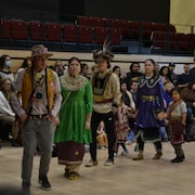 Des danseurs autochtones portent leur regalia lors d'un pow-wow auquel sont invitées plusieurs personnes.