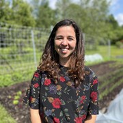 Elle regarde la cam&eacute;ra en souriant. En arri&egrave;re-plan, son jardin.