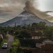 un volcan en éruption proche d'un village.