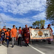Des gens marchent derrière une bannière de la Journée de la vérité et de la réconciliation.