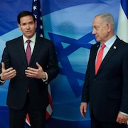 Deux hommes se tiennent devant des drapeaux am&eacute;ricain et isra&eacute;lien.