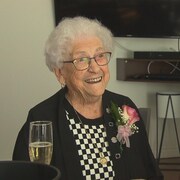 Une femme centenaire sourit à la caméra.