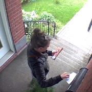 Marie-Eve Rancourt en train de prendre un tract du PQ dans une boîte aux lettres.