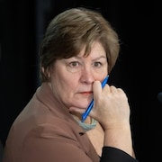 La commissaire Marie-Josée Hogue écoute, un stylo à la main, l'air pensif.