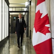 Mark Carney marche dans un couloir du parlement, à Ottawa.