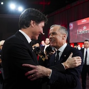 Justin Trudeau et Mark Carney sourient et se serrent la main.