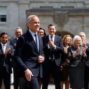 Le premier ministre canadien Mark Carney arrive pour une conférence de presse, tandis que les membres du nouveau Cabinet se tiennent derrière lui, à l'extérieur de Rideau Hall.