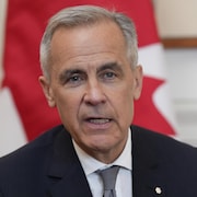 Mark Carney devant un drapeau canadien.