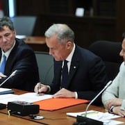 M. Carney signe un document.