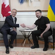 Mark Carney et Volodymyr Zelensky sont en train de se serrer la main.