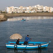 Un bateau en bois du Bou Regreg avec un passager sous un parasol.