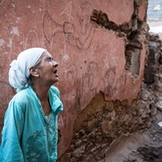 Une femme pleure devant les ruines. 