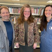 Légende : La conseillère Chantal Garneau est entourée de Maryse Mallet-Sinnis, à gauche, et Leanne Shelsen, à droite. Les trois femmes expliquent avoir à cœur le fait français à Georgetown. Les rayons de livres de la bibliothèque de Halton Hills forment l'arrière-plan.
