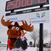 La mascotte Mouski tient dans ses mains une peluche, version miniature d'elle-même.