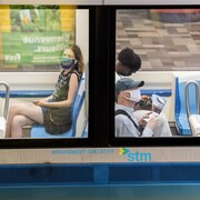 Dans un wagon de métro, des passagers.