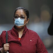 Une femme portant un masque dans la rue.