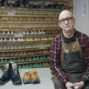 Un homme devant des moules de chaussures.