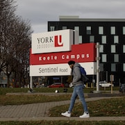 Un étudiant marche devant le panneau de l'Université York.