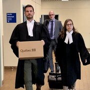 Vêtus de leur toge, les deux avocats de la poursuite marchent vers la salle d'audience.