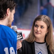 Une femme tend un micro à un joueur de hockey