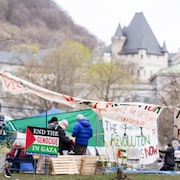 Des étudiants dans le campement de l'Université McGill, entourés de banderoles.