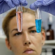 Une professionnelle du domaine médicale examine deux éprouvettes dans un laboratoire.