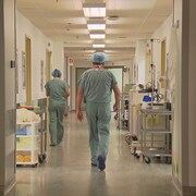Un médecin marche dans un corridor d'hôpital.