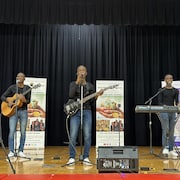 Trois musiciens sur une scène, instruments en main.