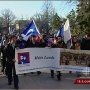 Groupe de Métis qui marchent dans une rue en tenant une banderole avec l'inscription « Métis Lands ».