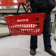 Une personne tient un panier d'épicerie Metro.