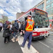 Un superviseur de la CTT regarde des gens entrer dans un autobus.