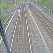 Capture vidéo de deux personnes courant sur les voies ferrées.