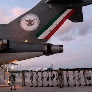 Des militaires qui entrent à la file dans un avion. 