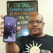 Michael Andrade montrant la photo des deux suspects sur son cellulaire.