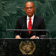 L'ancien président haïtien Michel Martelly se tient debout devant deux micros à la tribune de l'ONU. 