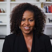 Michelle Obama est vêtue de noir et sourit. 