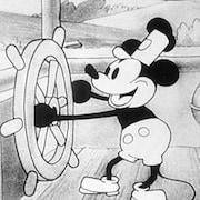 Le personnage de Mickey Mouse tient la barre d'un bateau. 