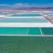 Des bassins de saumure et des zones de traitement d'une mine de lithium sont de couleur turquoise. À l'arrière-plan, il y a des montagnes.