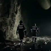 Deux travailleurs marchent dans une galerie de mine.