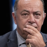 Christian Dubé, l'air pensif et la main sur la bouche, lors d'une conférence de presse.